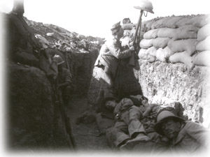 Life in the trenches. A soldier raises a helmet over the edge of a trench to see if it will draw enemy fire.